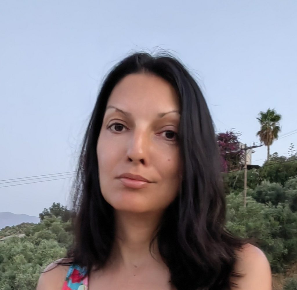 Portrait of Margarita, accountant at Aidos, outdoors with natural background, long dark hair, calm professional expression.